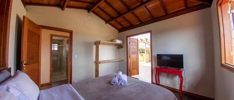 A bedroom with a bed, a television on a stand, and a door leading to an outdoor area.