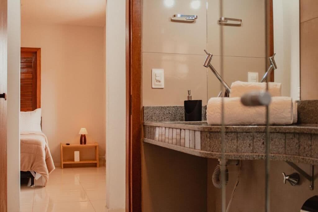 Baño de hotel con ducha, lavamanos y toallero.