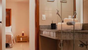 Baño de hotel con ducha, lavamanos y toallero.