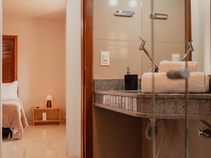 Baño de hotel con ducha, lavamanos y toallero.
