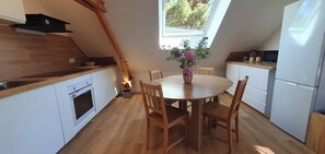 Eine kompakte Küche mit weißen Schränken, einem Holztisch und einem Fenster für natürliches Licht.