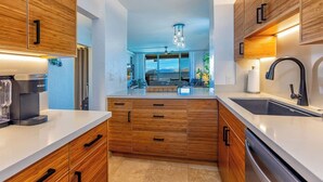 Una cocina moderna con armarios de madera, una cafetera integrada y vistas al área de estar.