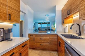 Eine moderne Küche mit Holzausstattung, einer integrierten Kaffeemaschine und Blick zum Wohnbereich.