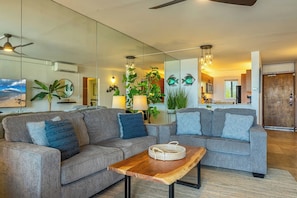 Ein modernes Wohnzimmer mit zwei grauen Sofas, einem Holztisch und einem Deckenventilator.