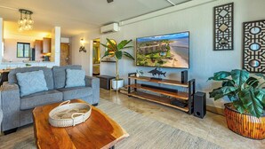Una sala de estar moderna con un sofá gris, una mesa de centro de madera y un televisor montado en la pared.