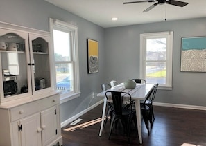 Un coin repas avec une table blanche, des chaises noires et un ventilateur de plafond.