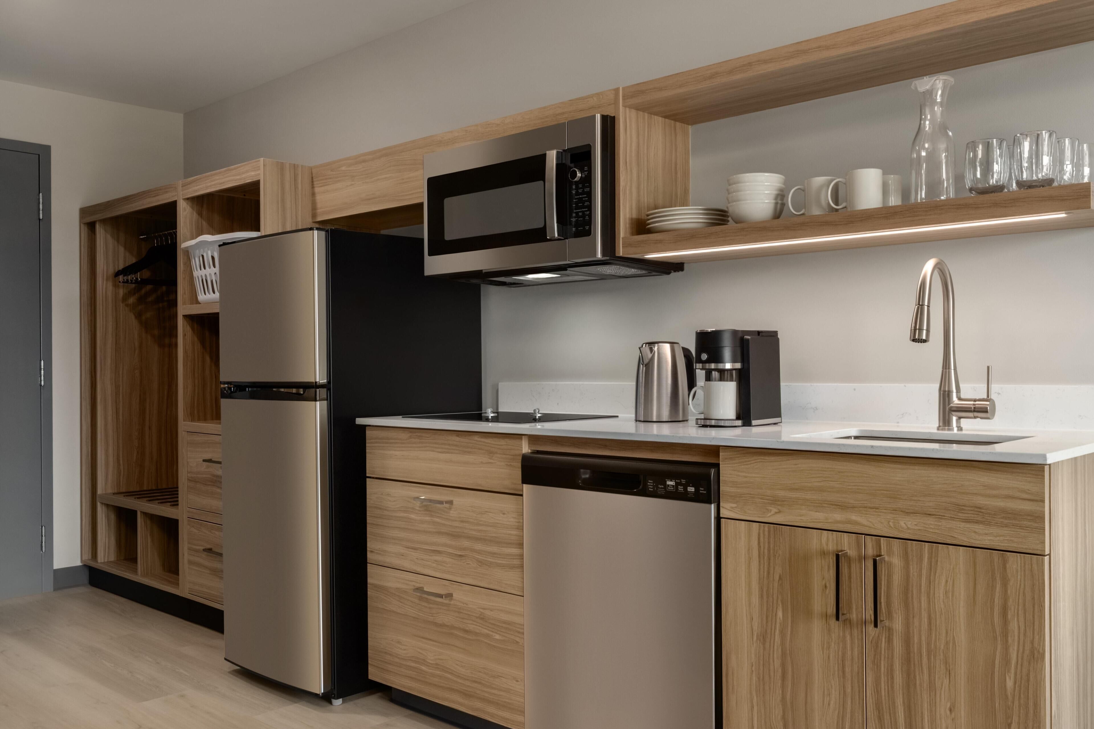 A modern kitchen with stainless steel appliances, wooden cabinetry, and a built-in microwave.