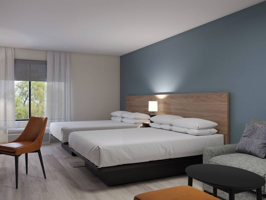 Habitación de hotel con dos camas, un escritorio, una silla, un sofá y una mesa de centro.