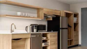 Una cocina moderna con armarios de madera, un refrigerador de acero inoxidable, un microondas y una cafetera.