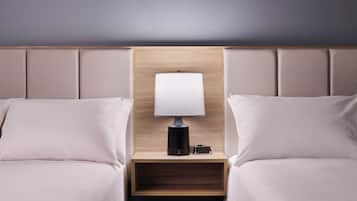 A hotel room with two beds, a nightstand with a lamp, and a wooden headboard.