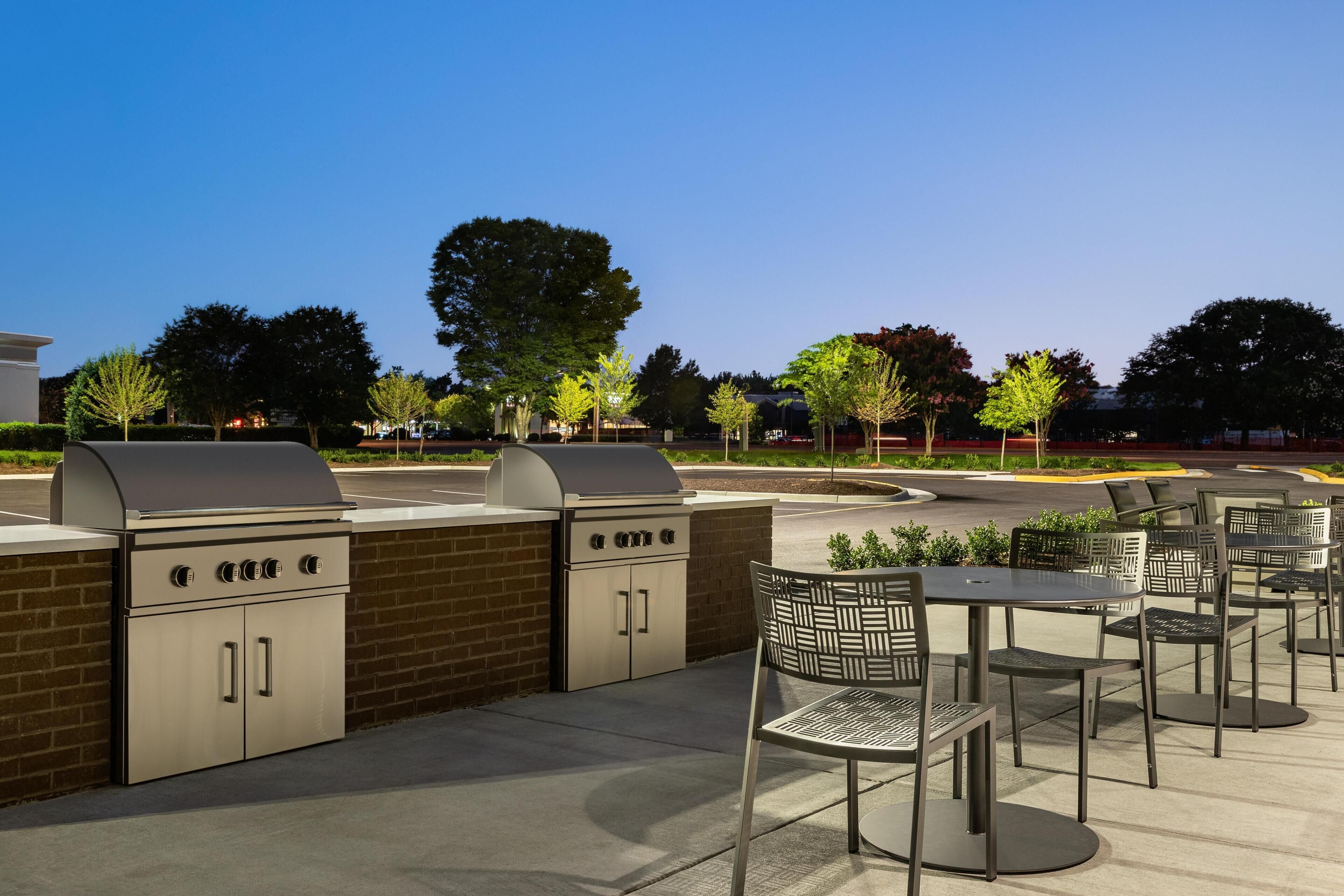 An outdoor patio area with barbecue grills and metal chairs.
