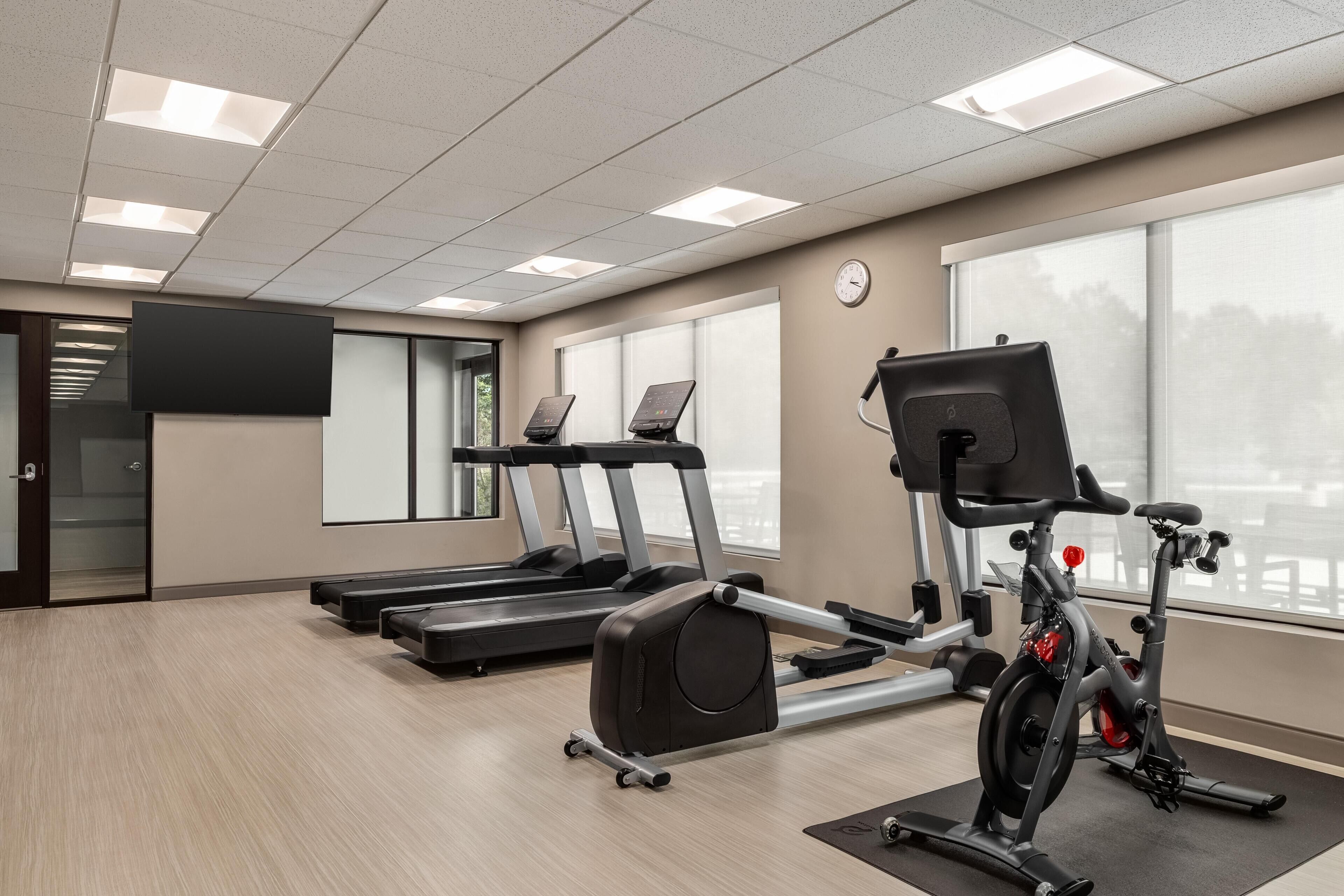Une salle de sport équipée de tapis de course, d’un vélo elliptique et d’un vélo d’appartement.