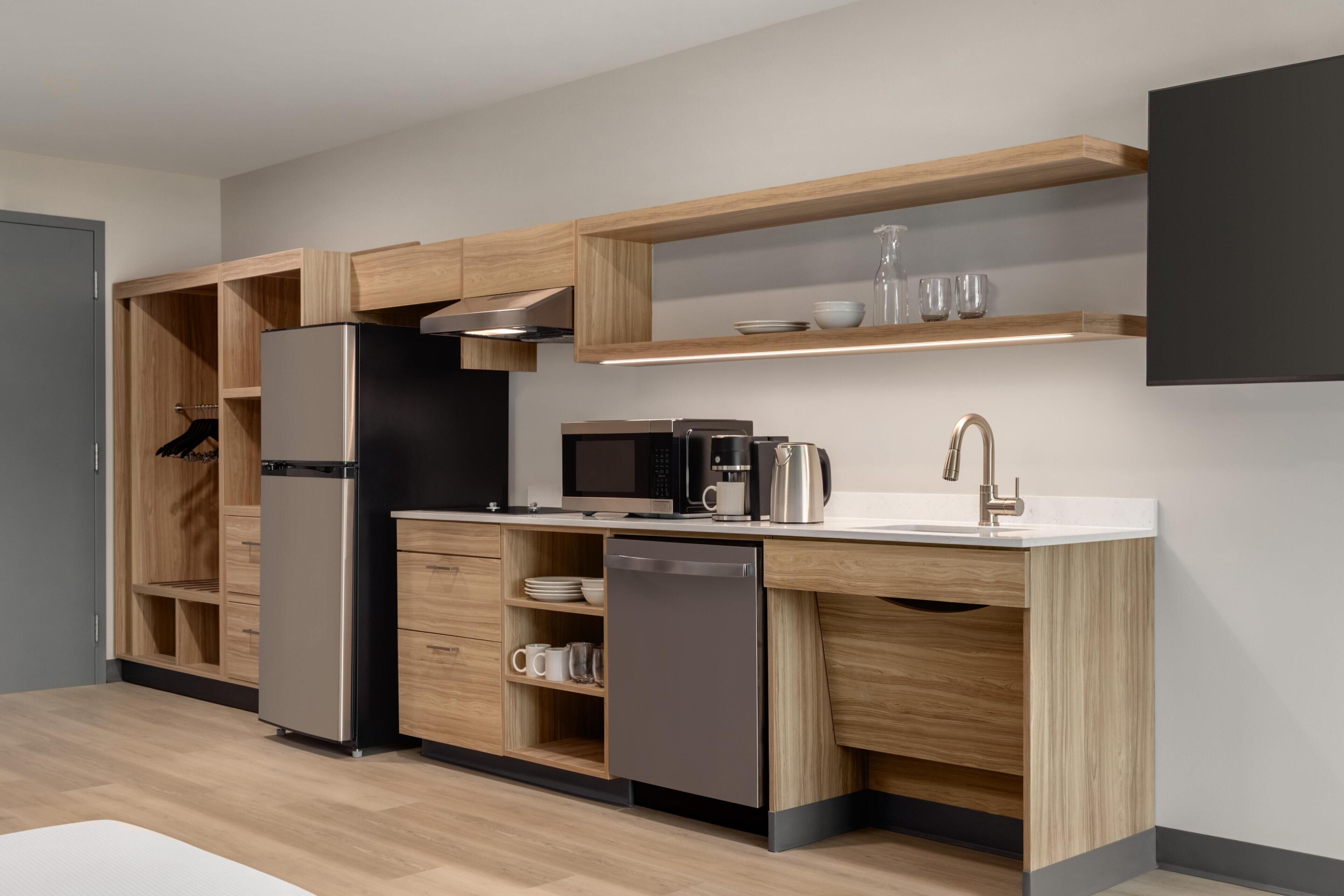 A modern kitchen with built-in appliances, wooden cabinetry, and a countertop with a sink and coffee maker.