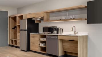 A modern kitchen with built-in appliances, wooden cabinetry, and a countertop with a sink and coffee maker.
