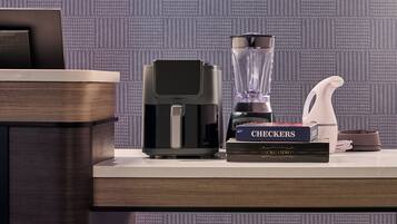 A kitchen area with a coffee maker, a blender, a kettle, and a book titled 'CHECKERS' on a countertop.