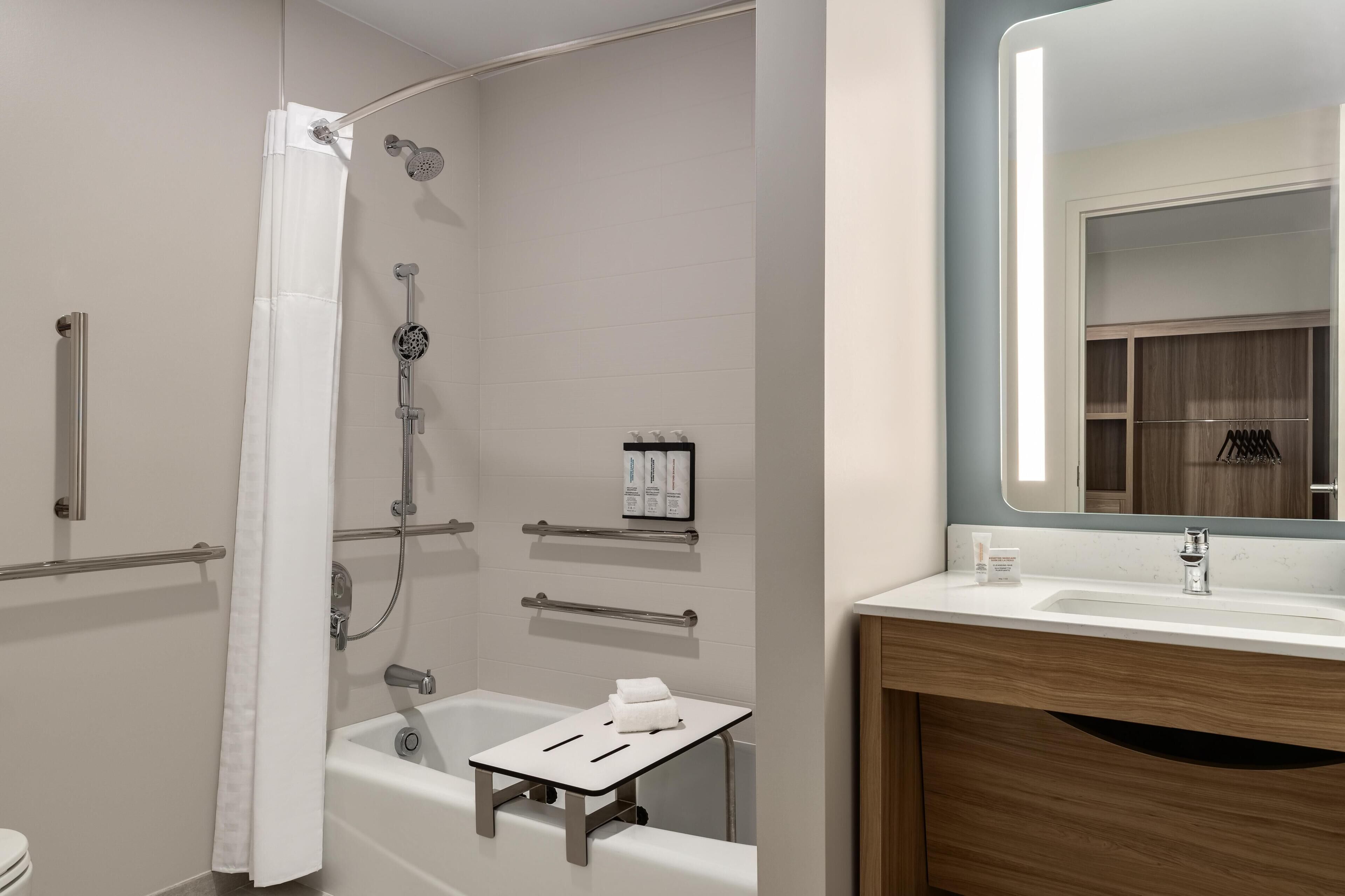 Un baño moderno con bañera, ducha y tocador con espejo.