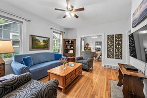 A living room with a sofa, armchair, coffee table, and a ceiling fan. - Walk to Brevard | Fenced Yard + Relaxing Porch (Brevard)
