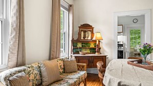 Una habitación con sofá, mesa de comedor de madera, zona de cocina y vistas al exterior.