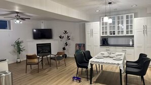 Eine moderne Küche mit weißen Schränken, einem Esstisch mit Stühlen und einem Deckenventilator.