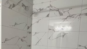 Ein Badezimmer mit Badewanne, Dusche und Handlauf.