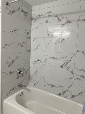 A bathroom with a bathtub, a shower, and a handrail. - Entire Basement | 2BR | Private Entry | Cozy Stay (Calgary)