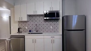 Eine moderne Küche mit weißen Schränken, einem Edelstahl-Kühlschrank, einer Mikrowelle und einem Geschirrspüler.