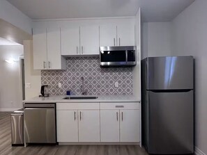 A modern kitchen with white cabinets, a stainless steel refrigerator, a microwave, and a dishwasher. - Entire Basement | 2BR | Private Entry | Cozy Stay (Calgary)