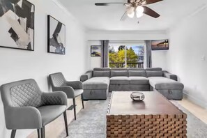Ein modernes Wohnzimmer mit einem Ecksofa, einem Couchtisch und Kunstwerken an den Wänden.