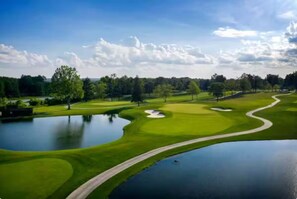Ein Golfplatz mit Teichen, Bäumen und blauem Himmel.
