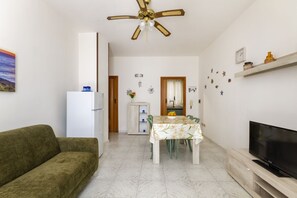 A living room with a sofa, a dining table with chairs, a television, and a ceiling fan. - This colorful and welcoming apartment, ideal for up to 4 people, is strategically located in Lecce: outside the restricted traffic zone but just steps from the historic center. Just 400 meters from Porta San Biagio, it's easy to immerse yourself in the w (Otranto)