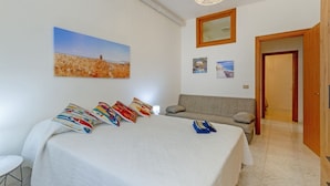 A bedroom with a large bed, a sofa, a painting, and a door. - This colorful and welcoming apartment, ideal for up to 4 people, is strategically located in Lecce: outside the restricted traffic zone but just steps from the historic center. Just 400 meters from Porta San Biagio, it's easy to immerse yourself in the w (Otranto)