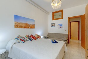 Ein Schlafzimmer mit einem großen Bett, einer Couch, einem Gemälde und einer Tür.