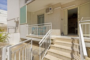 Ein Hotel Eingang mit Treppe, einem Balkon mit Geländer und einer Klimaanlage.