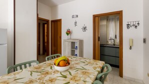 A dining area with a table, chairs, a fruit bowl, a cabinet, and a kitchen visible through an open door. - This colorful and welcoming apartment, ideal for up to 4 people, is strategically located in Lecce: outside the restricted traffic zone but just steps from the historic center. Just 400 meters from Porta San Biagio, it's easy to immerse yourself in the w (Otranto)