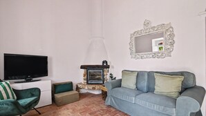 Ein Wohnzimmer mit Fernseher, Kamin aus Stein, einer Couch und einem dekorativen Spiegel.