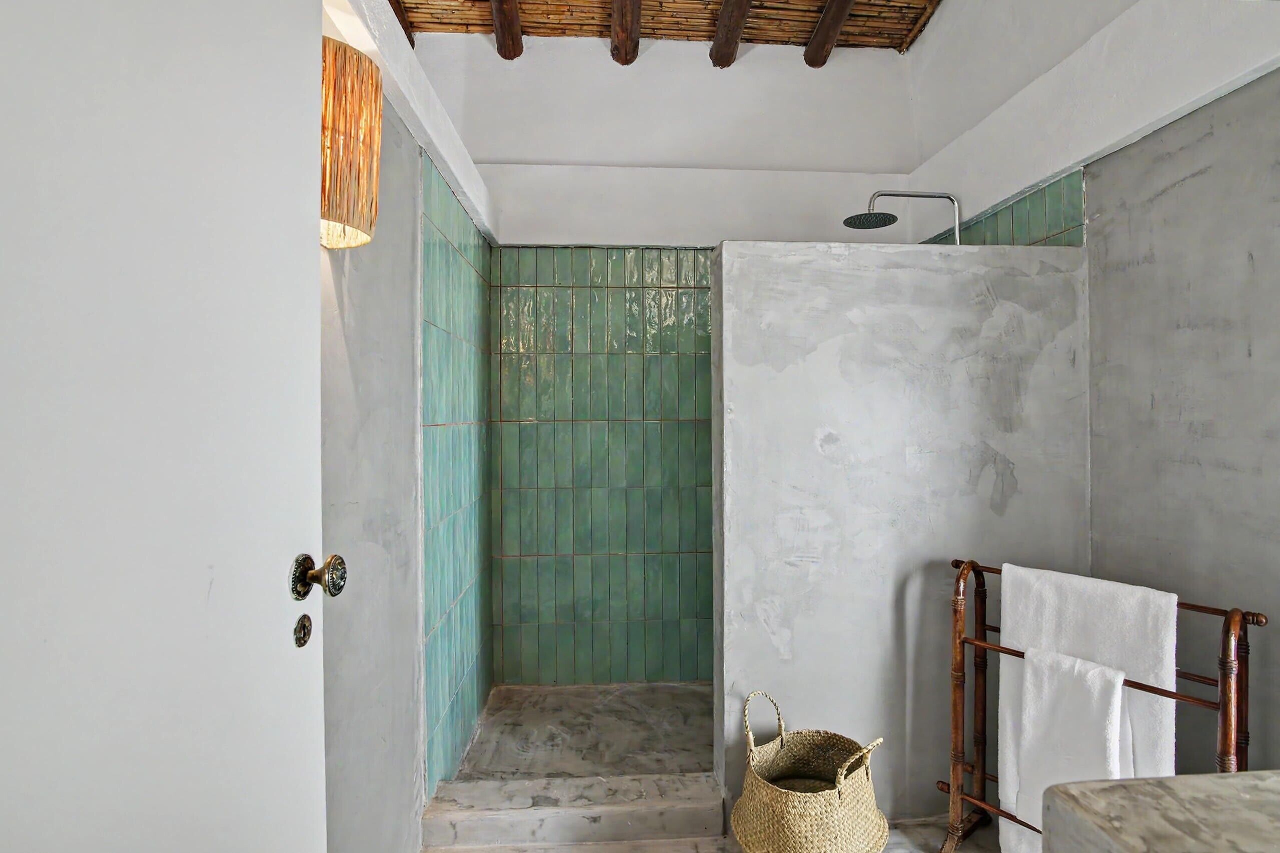 A bathroom with a shower, a wooden towel rack, and a woven basket.
