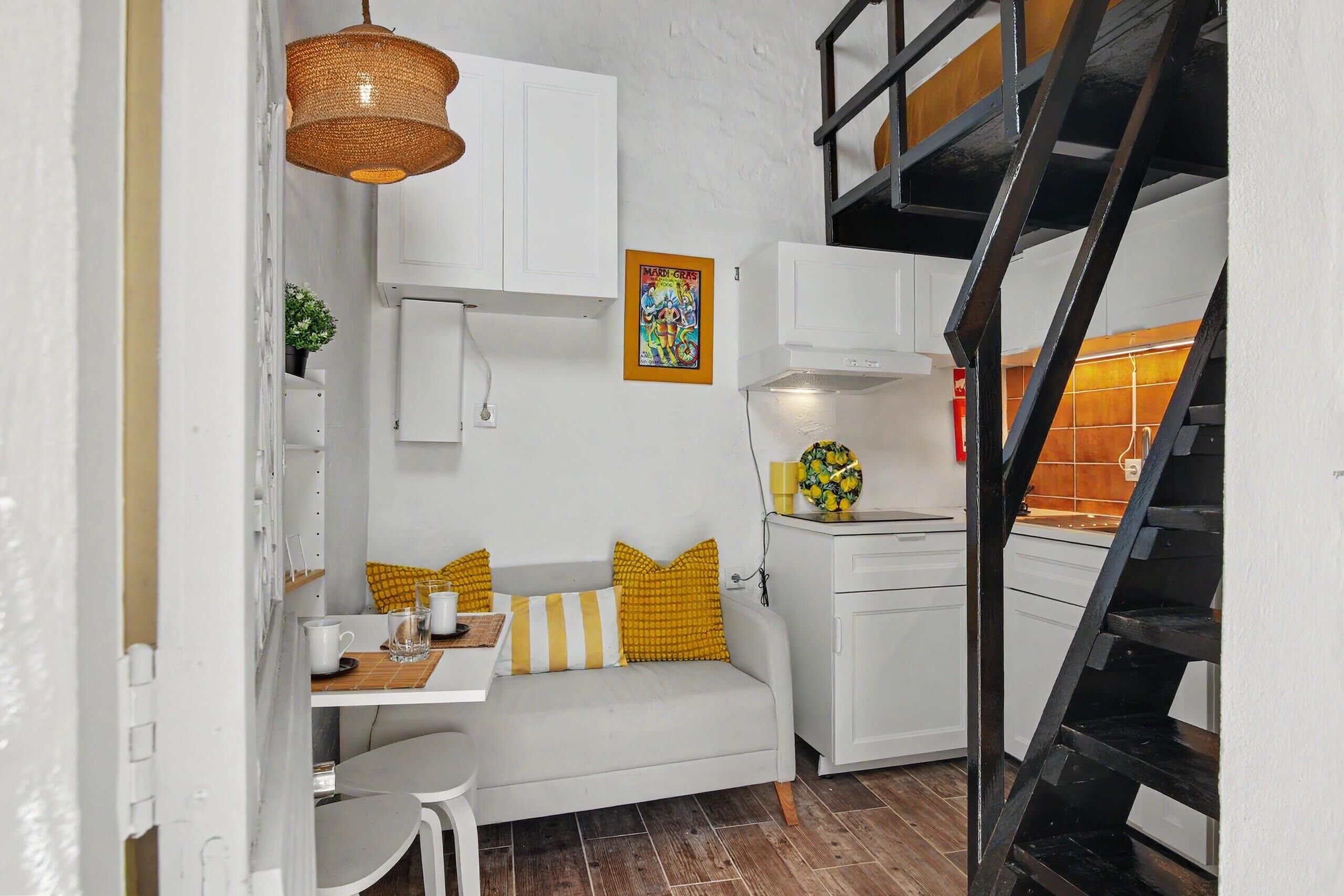 A compact living space with a kitchenette, a dining area, and a staircase.