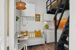 A compact living space with a kitchenette, a dining area, and a staircase.