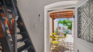 Una scala conduce a una stanza con vista su uno spazio esterno, un tavolo con sedie e una finestra con decorazioni in ferro battuto.