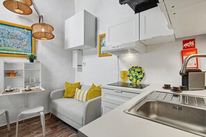 Una cocina moderna con armarios blancos, estufa integrada y pileta de acero inoxidable.