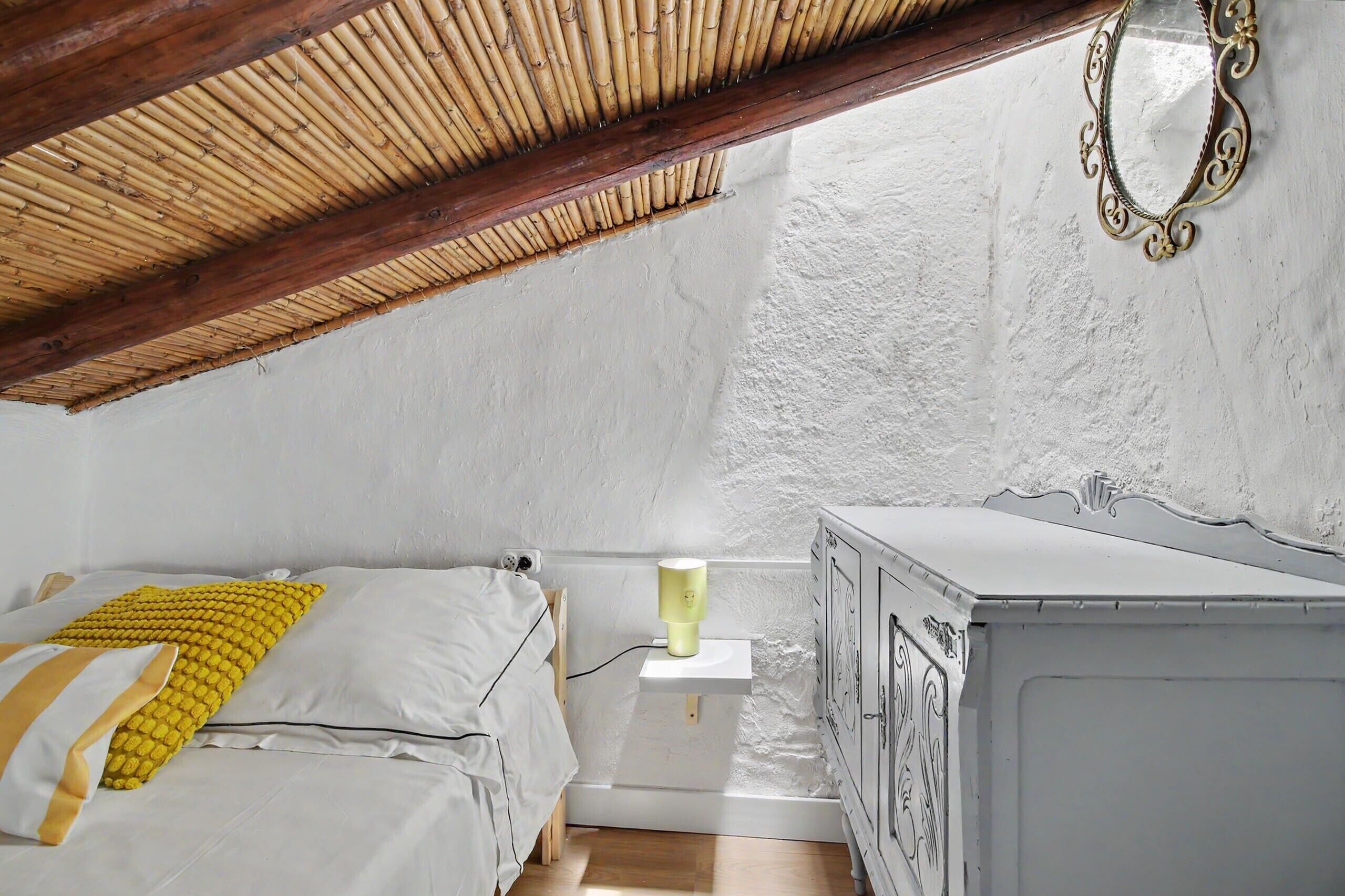 A bedroom with a bed, bedside table, and a wardrobe.