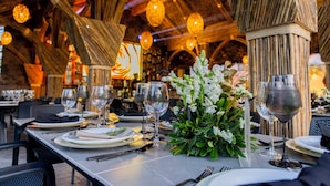 Interior de un restaurante con mesas dispuestas para comer, destacando un techo rústico y lámparas colgantes.