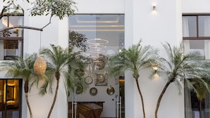 Un edificio moderno con mostrador de recepción, palmeras y detalles artísticos en la pared.