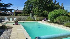 A swimming pool with a pool cover, lounge chairs, and a garden area. - Gîte Les Magnolias Logis Bourseguin, private terrace and Wi-Fi (Bourneau)