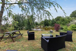 Ein Picknickplatz mit Tisch und Stühlen, umgeben von Bäumen und einem Teich.