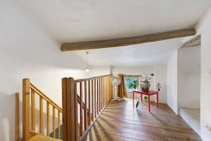 Eine Holzt Treppe mit Handlauf, ein Ventilator und ein Tisch mit einer Pflanze.