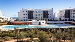 Un hotel moderno con piscina, varios pisos y vista al mar.