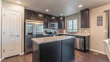 A modern kitchen with dark cabinets, stainless steel appliances, and a central island.