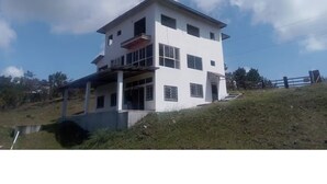 A multi-story building with a flat roof, large windows, and a balcony on the upper floor.