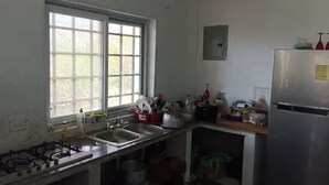 A kitchen with a gas stove, sink, window, and a refrigerator.